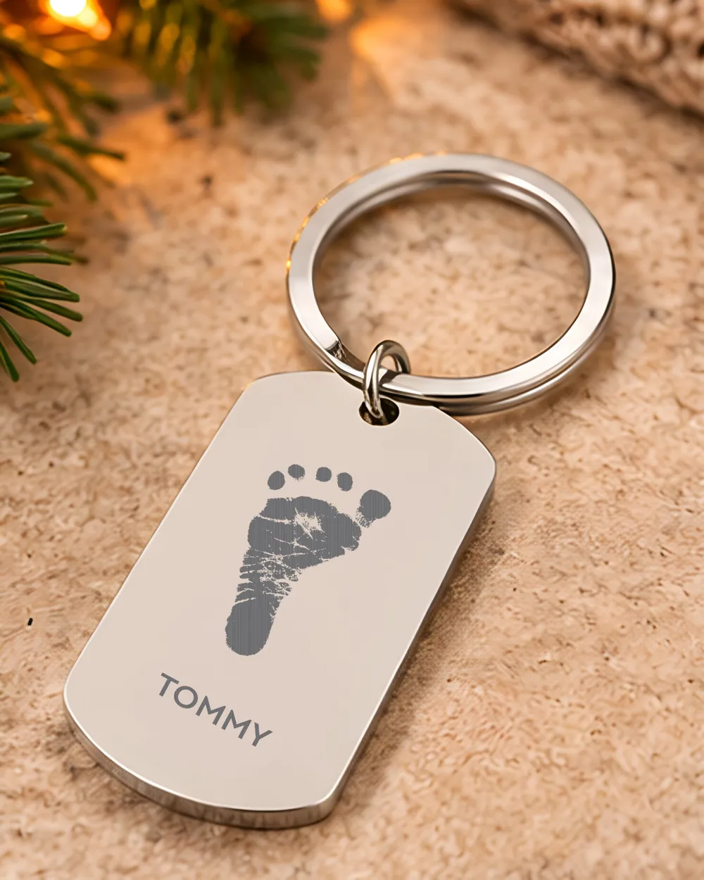 A silver engraved keyring with a baby's footprint and the name Tommy