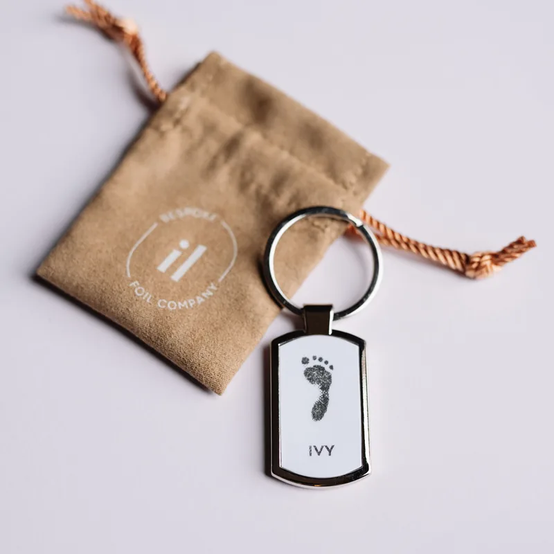 A personalised footprint keyring with a branded Bespoke Foil Company pouch